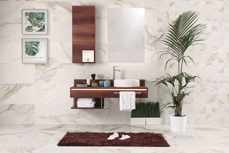 Helle Fliesen in Marmoroptik an Wand & Boden in einem Badezimmer mit Blick auf einen Waschtisch in Holzoptik, einem Läufer in der Farbe Braun davor, einem Spiegel, Bildern an der Wand & Pflanzen