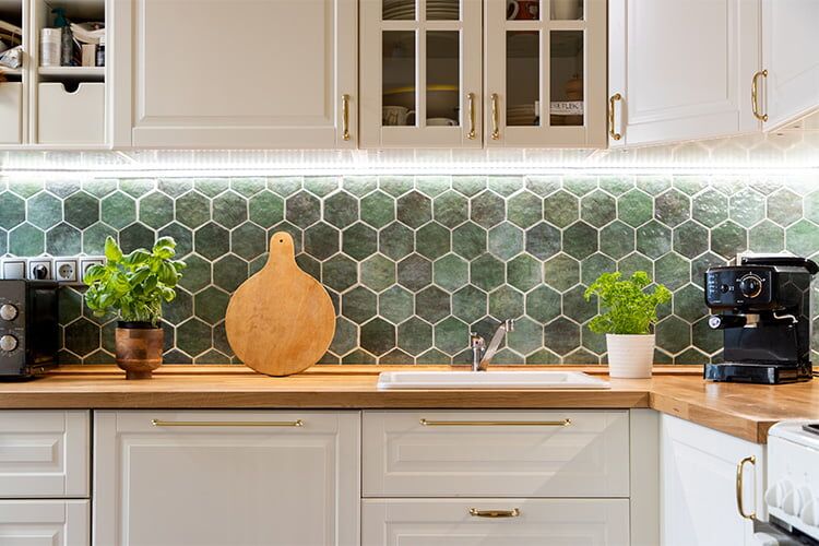 Weiße Landhausküche mit Fliesenspiegel aus grünen Sechseckfliesen