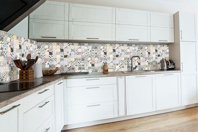 Weiße Küche mit buntem Fliesenspiegel aus Vintagefliesen