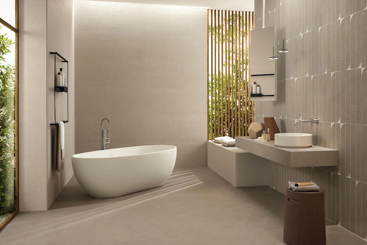 Boost Natural Fliesen in einem Badezimmer mit freistehender Badewanne, einem modernen Waschbereich und bodentiefen Fenstern mit Blick ins Grün