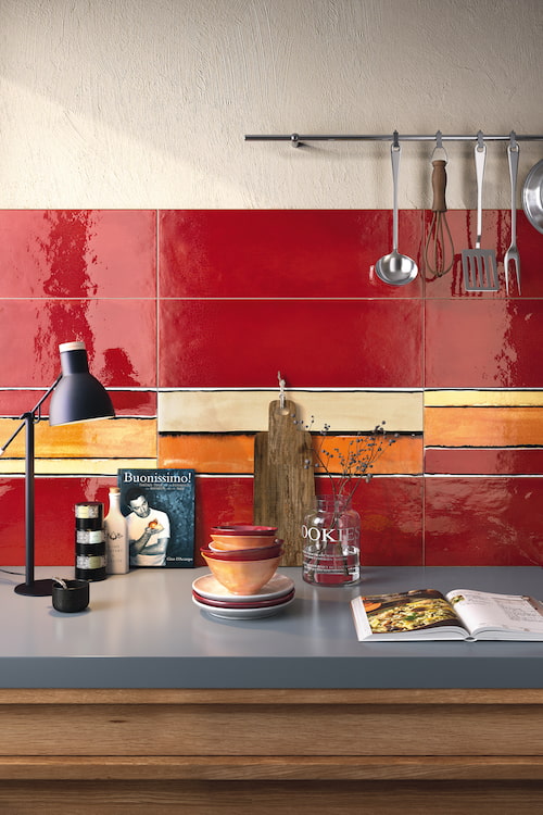 Küchenzeile mit grauer Arbeitsplatte und buntem Fliesenspiegel in kanlligem Rot, Orange und Gelb